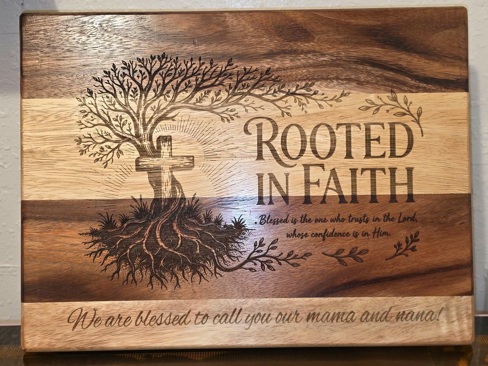 Two-tone walnut board engraved with a tree, a cross, and Rooted in Faith